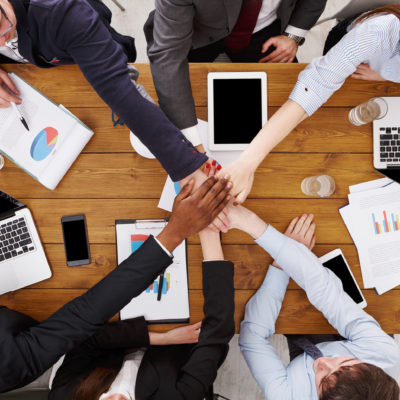 Multiethnic Team put hands together, connection, teambuilding and alliance concept. People in the office, young businessmen and women unite hands for teamwork and cooperation. Top view, overhead